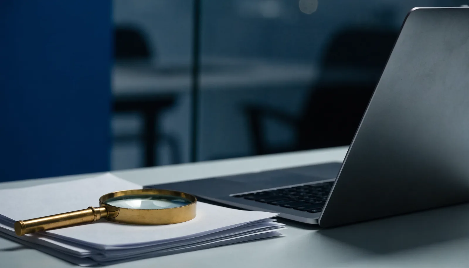 Laptop and magnifying glass over documents on a desk, representing a California criminal background check